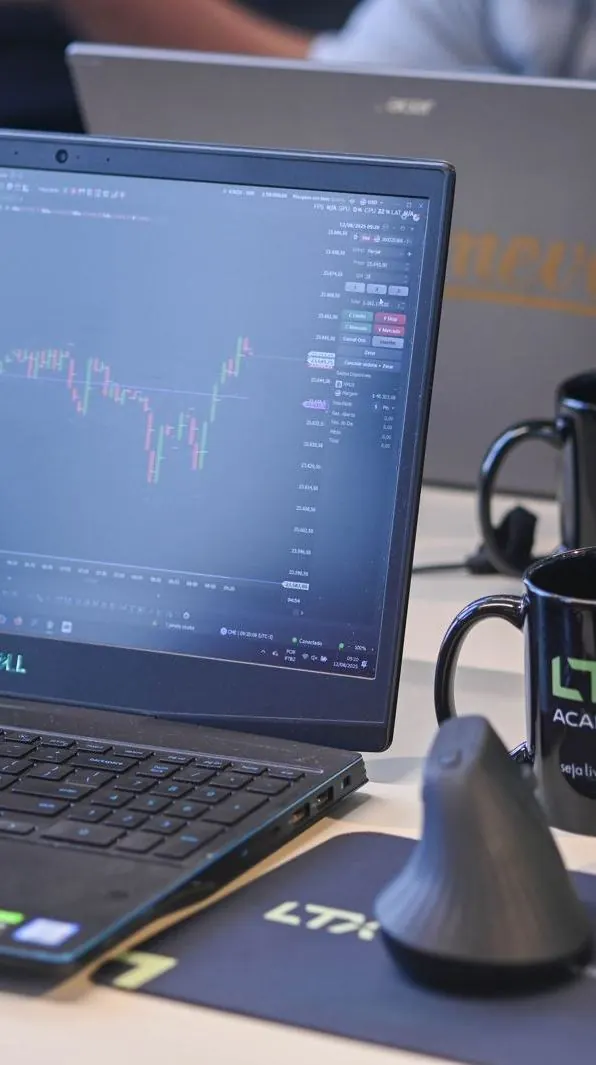 Notebook com gráfico de day trade ao lado de canecas da LTX Academy