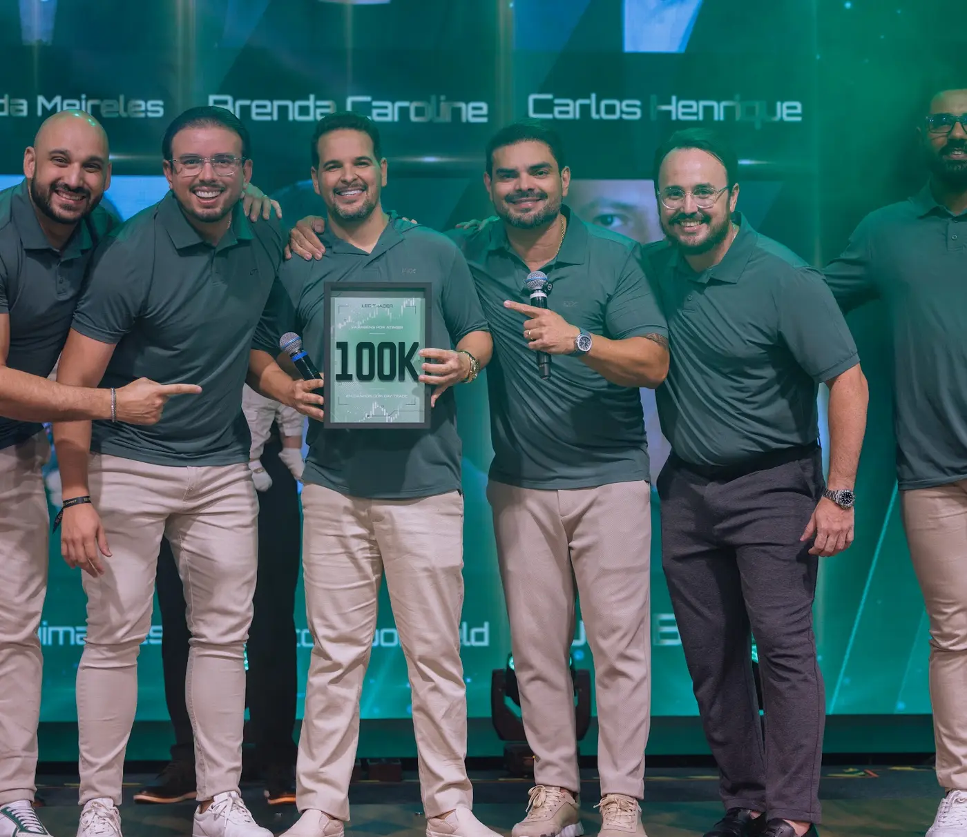 Traders apontando para a placa de 100K no palco