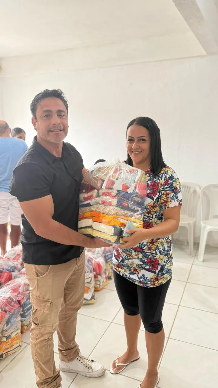 Voluntário entregando uma cesta básica a uma moradora