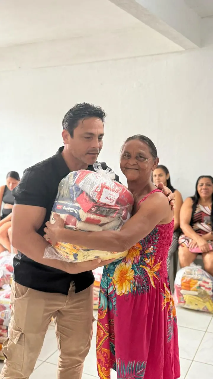 Voluntário e senhora abraçados segurando uma cesta