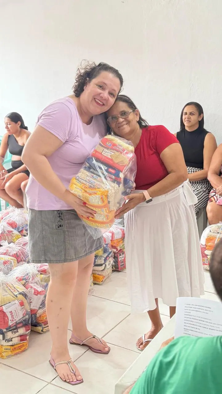 Duas mulheres abraçadas com uma cesta básica