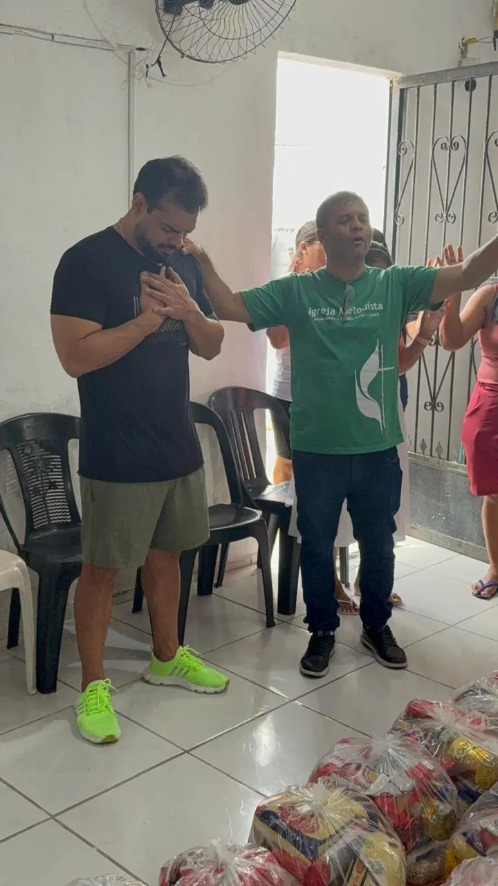 Voluntários orando juntos no salão durante a entrega