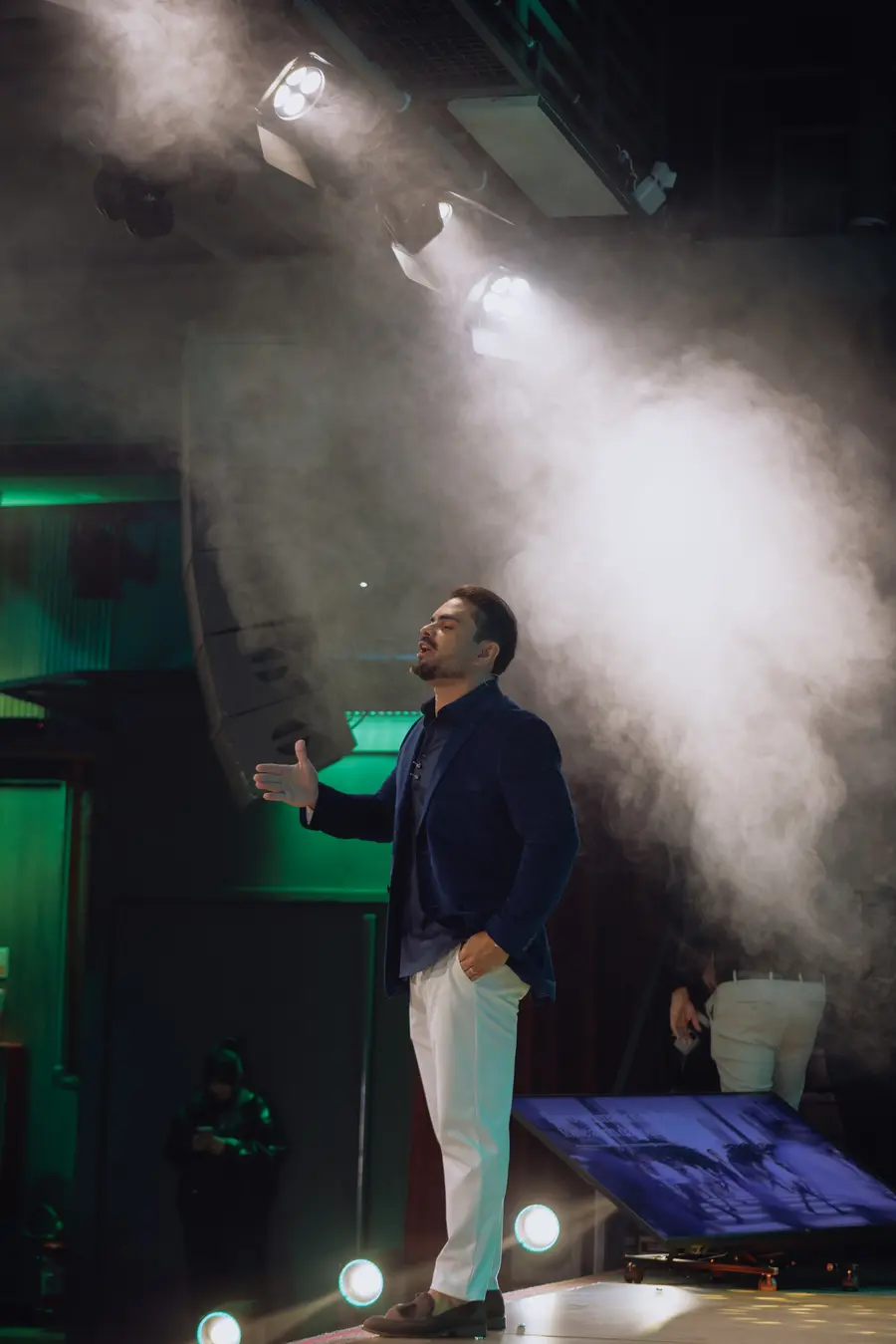 Palestrante sob um feixe de luz com fumaça no palco