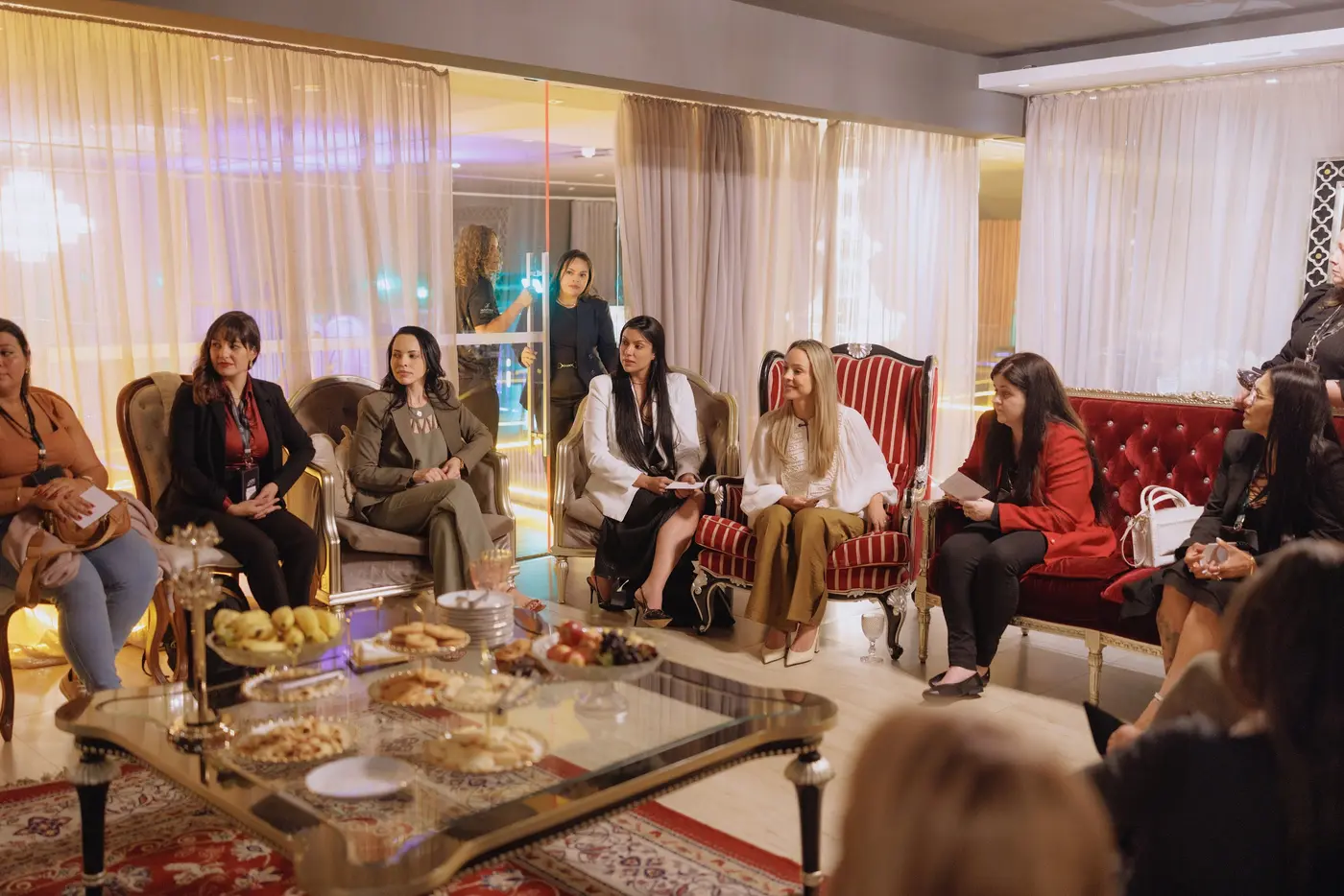 Lounge feminino com sofás vermelhos e participantes conversando