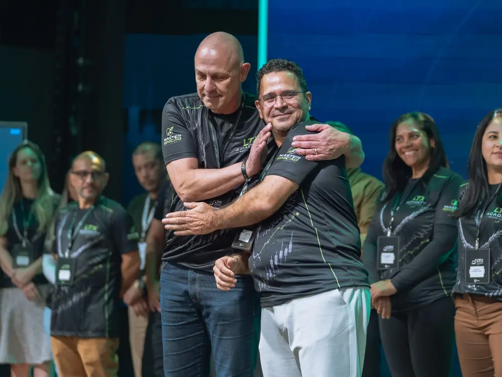 Dois homens de camiseta do time se abraçando e sorrindo