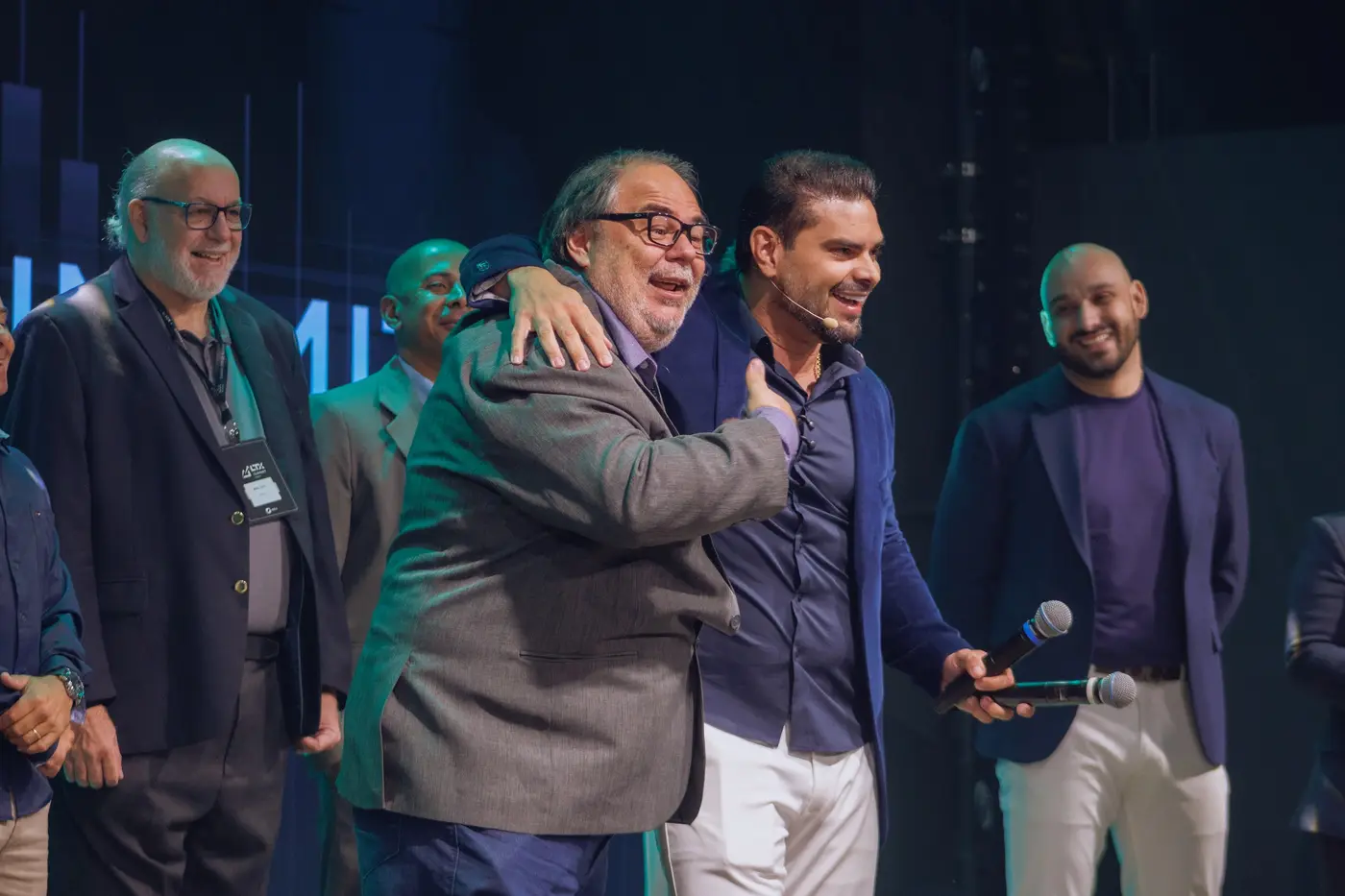 Dois homens se abraçando e rindo no palco