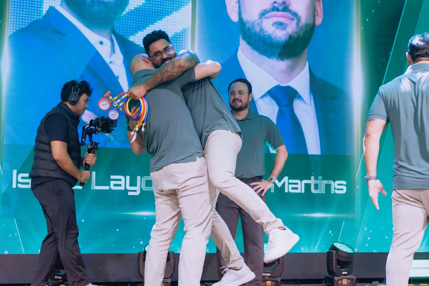 Dois traders se abraçando e saltando no palco durante a premiação